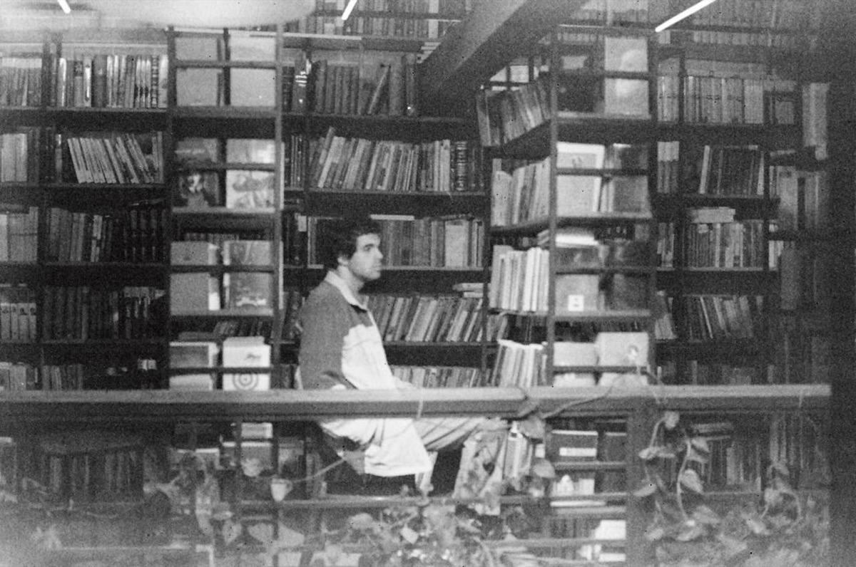 Bezoeker in een bibliotheek tussen volle boekenkasten